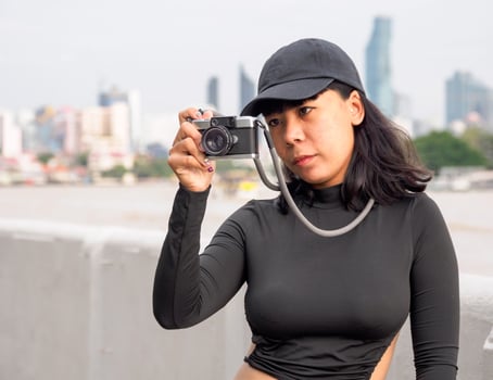 Portrait tourist young woman Asian wearing black hat and black dress with retro film camera  to take pictures. Save memories of your travels photo