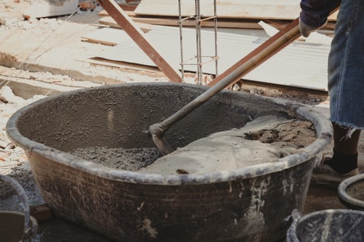 Worker man house builder mix mortar from a trough in bucket photo
