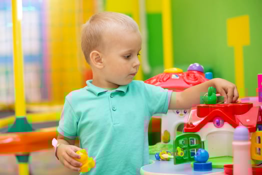 A little boy plays with a lot of colorful plastic toys indoors. photo