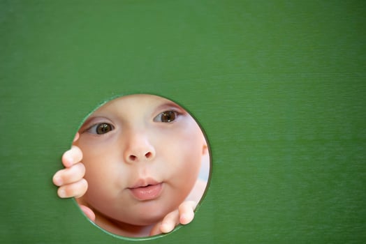 A little girl peeks through a hole. The face of a child in a circle. photo