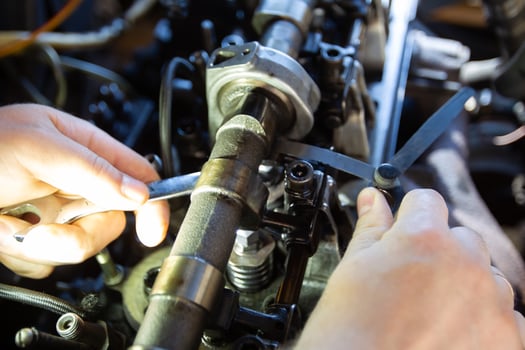 Mercedes diesel engine repair. Hands with a mechanic repairing Mercedes parts. Valve clearance adjustment. photo