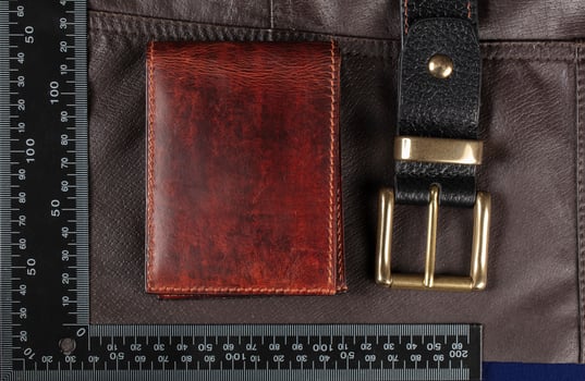 Leather goods purse and belt against the background of a ruler for cutting and sewing. photo