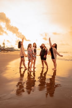 a group of Asian women in shirts posing happily while visiting a beautiful beach photo