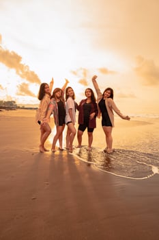 a group of Asian women in shirts posing happily while visiting a beautiful beach photo
