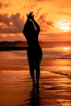 the silhouette of an Asian teenager with a tall body is dancing ballet on the waves on the beach photo