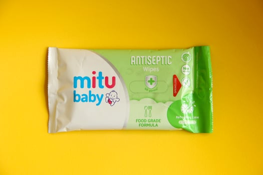 West Jakarta, Indonesia - February 10th, 2023 - Travel size tisu basah baby wipes green food grade in small plastic packaging. Hygiene product for children. Photo isolated on yellow background.