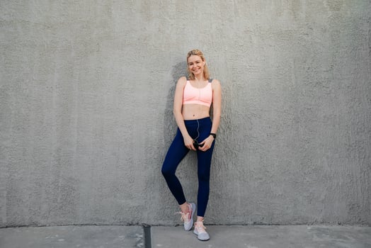 A sportive girl stands near the wall with a phone in her hands photo