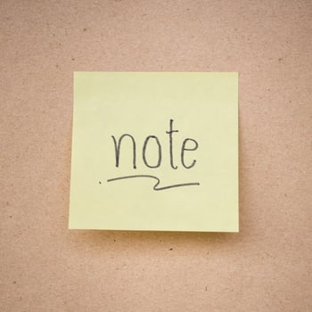 yellow sticky note on brown paper texture close up photo