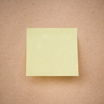 yellow sticky note on brown paper texture close up photo