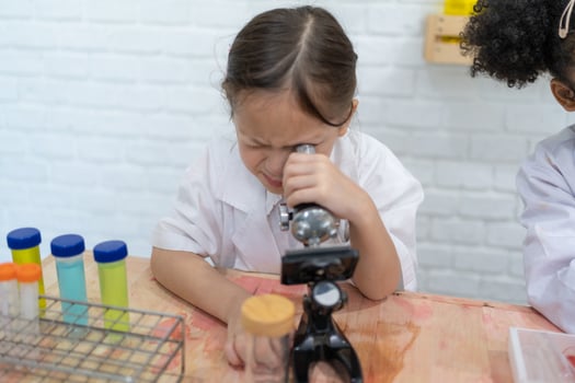 Two little kids in lab coat learning chemistry in school laboratory. Young scientists in protective glasses making experiment in lab or chemical cabinet. Working on a tablet. photo