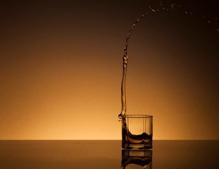 Glass of alcoholic drink on a golden background photo