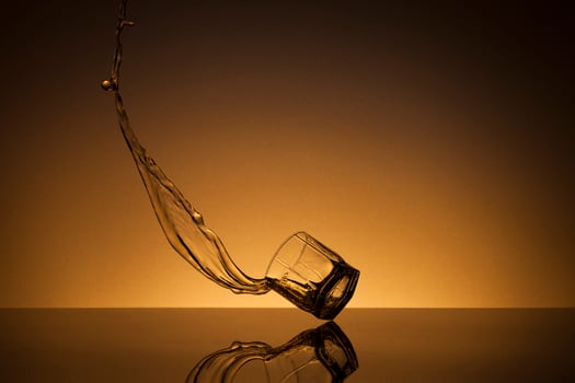 Falling glass of alcoholic drink on a golden background photo