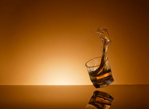 Falling glass of alcoholic drink on a golden background photo