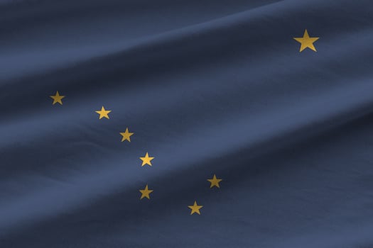 Alaska US state flag with big folds waving close up under the studio light indoors. The official symbols and colors in banner photo