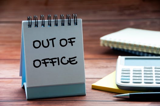 Out of office text on calendar desk with notebook, calculator and pen background. Out of office concept. photo