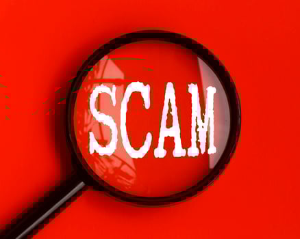 Scam text on red cover with magnifying glass. Scamming and fraud concept photo