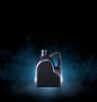 Black bottle of engine oil on black background with smoke photo
