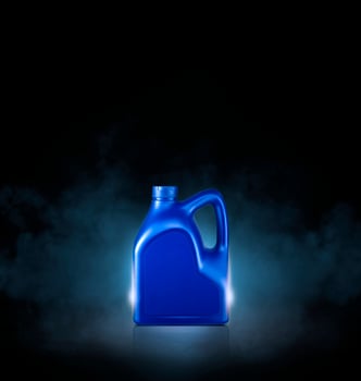 Blue bottle of engine oil on black background with smoke photo