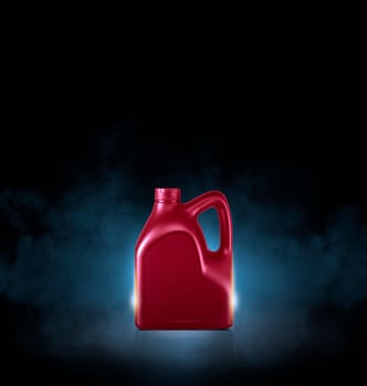 Red bottle of engine oil on black background with smoke photo