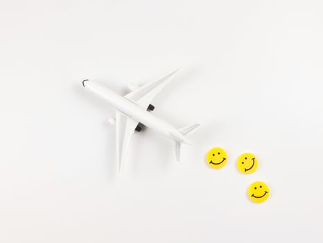 flat lay of airplane model with three yellow circle smiling faces  on white  background. Happy or fun trip concept. photo