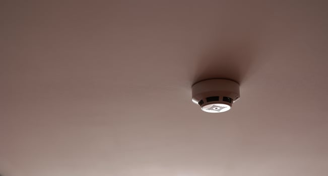 Fire system indoors. White smoke detector issue a signal to a fire alarm control panel as part of a fire alarm system installed on the white ceiling in the office building or apartment. photo