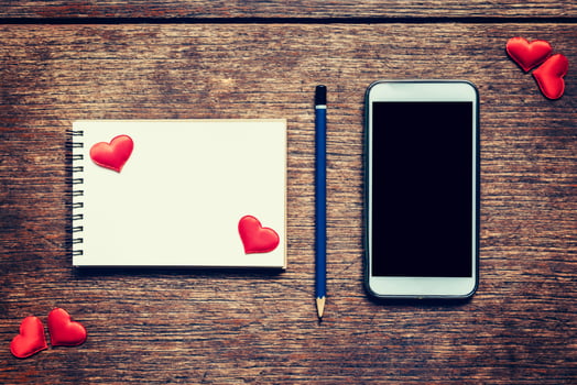 Empty notebook, pencil and red heart on wood table with phone blank copy space screen for your advertising. Valentine background. photo