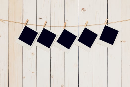 Five blank photo frame hanging on white wood background with space.