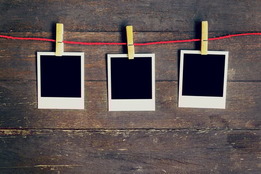 Three blank photos frame hanging on the clothesline. On old wood background.
