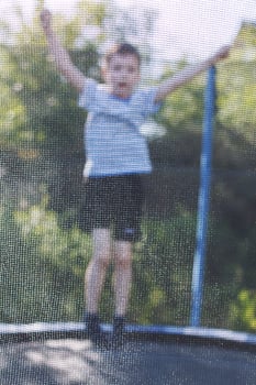 boy jumping on trampoline. the child plays on a trampoline outdoor photo