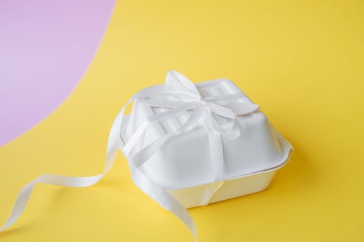 A bento cake box with a wooden spoon stands closed on a yellow background photo