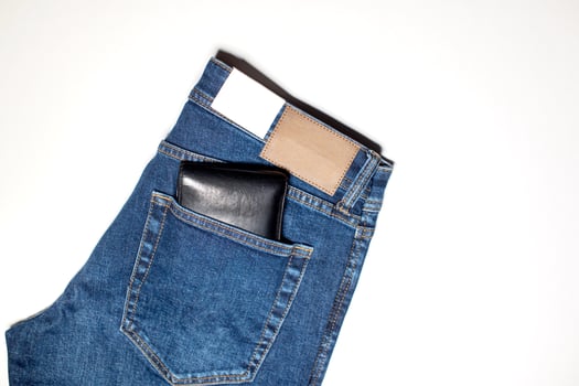 A pair of denim trousers with an empty leather label, a wallet in the back pocket. photo