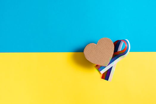 The concept is no war in Ukraine. Cardboard heart and ribbon of the Russian flag on the background of the Ukrainian flag. Top view. photo