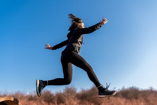 young female runner is jumping over wooden hurdles in countryside photo