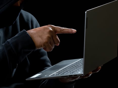 Computer and hands of a man wearing a black shirt, sitting on a chair and a table, is a thief, holding money, counting the amount obtained from hijacking or robbing, in a pitch-black room. photo
