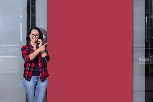 Woman talking with the mobile while pointing to a banner in a window shop photo