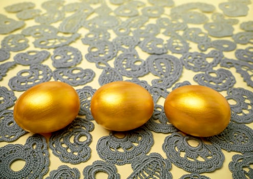 Golden Easter eggs on vintage lace background. The concept of a bright Easter photo