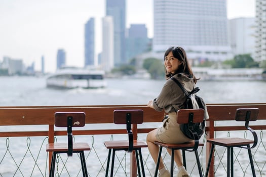 Young Asian woman backpack traveler waiting an express boat at pier on Chao Phraya River in Bangkok. photo