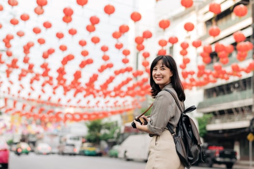 Young Asian woman backpack traveler enjoying China town street food market in Bangkok, Thailand. Traveler checking out side streets. photo