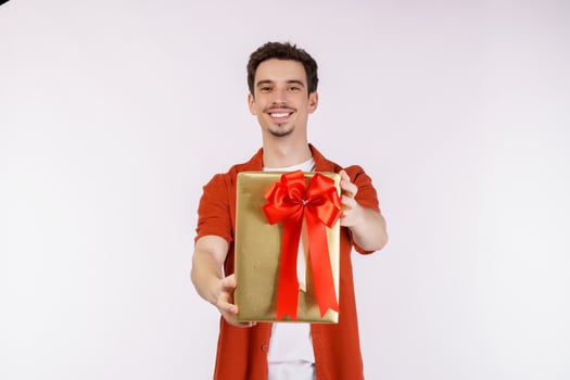 Portrait of Happy young caucasian man showing present box and looking at camera isolated over white background photo