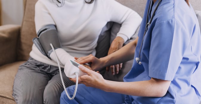 Homecare nursing service and elderly people cardiology healthcare. Close up of young hispanic female doctor nurse check mature caucasian man patient heartbeat using stethoscope during visit photo