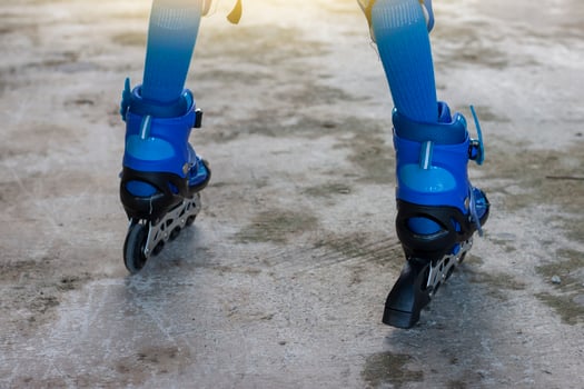 Little boy learning roller skate by wearing blue roller skate shoes on cement floor. photo