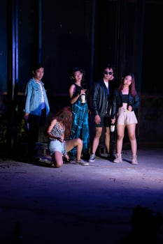 a group of teenagers taking a photo together with a purple light in front of a bar
