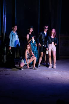 a group of teenagers taking a photo together with a purple light in front of a bar