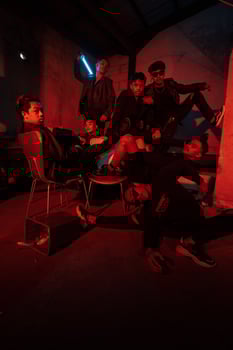 a group of Asian teenagers in black clothes posing very naughty with their friends in a warehouse with a red light photo