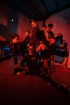 a group of Asian teenagers in black clothes posing very naughty with their friends in a warehouse with a red light photo