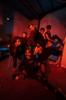 a group of Asian teenagers in black clothes posing very naughty with their friends in a warehouse with a red light photo