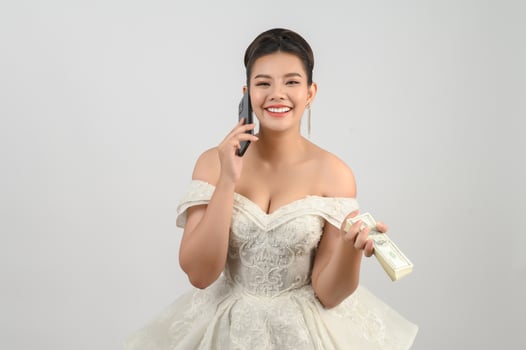 Young asian beautiful bride posting with smartphone and banknote in hand photo