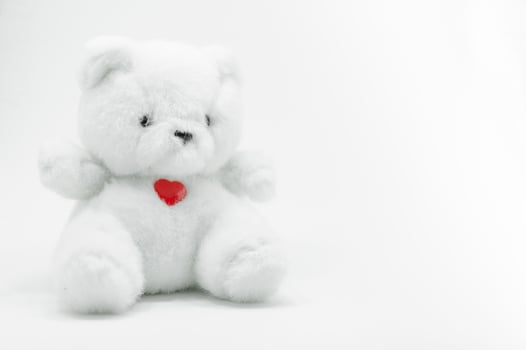 Lovely white teddy bear toy sitting with red heart on white background, fall in love teddy bear. photo