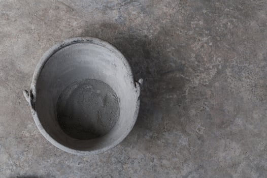 Plastic bucket with cement placed on an old cement floor.the house wall on the construction site photo