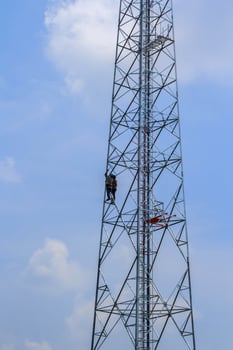 Painting cell phone antennas and the internet to enhance beauty by young hard-bodied laborers with audacity to reach heights is a dangerous job. photo